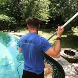 A technician skims debris from a pool during weekly maintenance