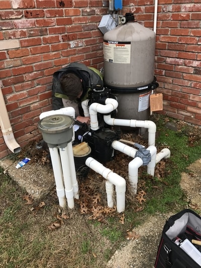 A technician works on a pool plumbing repair