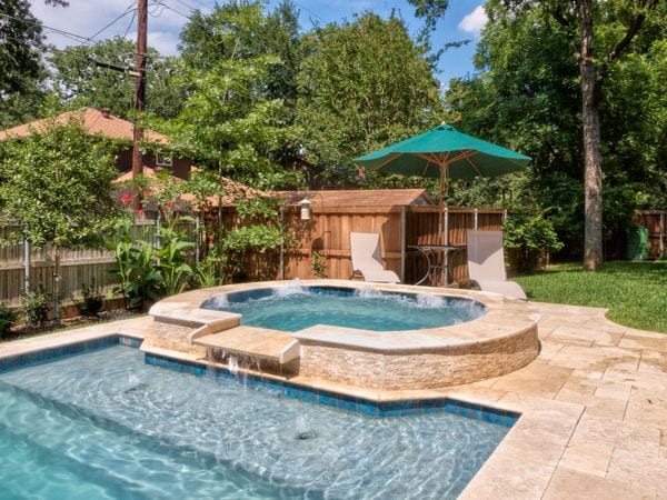 A beautiful spa connected to a rectangular swimming pool.