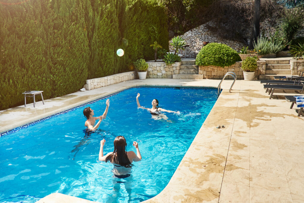 woman throwing ball with son and daughter in swimming pool